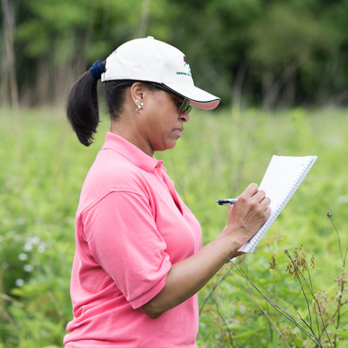 Student taking notes in outdoor setting