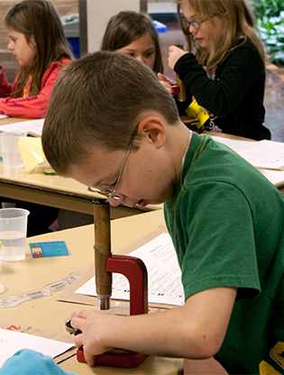 Boy looking at soil through a microscope