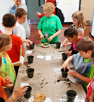 Volunteer assisting students with planting activity